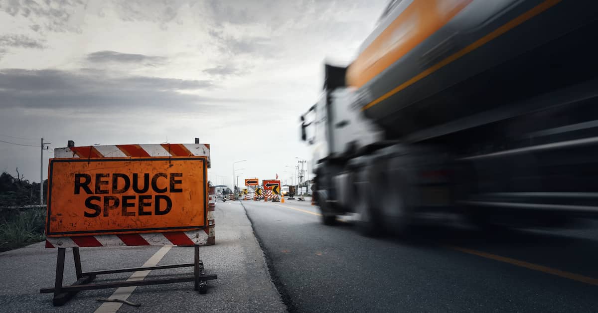 truck drives past "reduce speed" sign | Oliver Law Firm