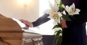 person rests hand on casket | Oliver Law Firm