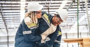 Female construction worker helping male coworker after an on-the-job injury | Oliver Law Firm